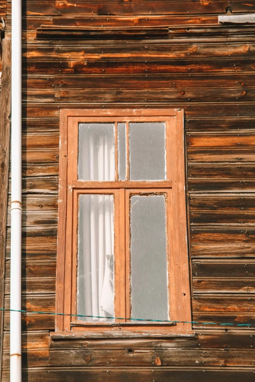 a large wood framed window sitting on the side of a wooden house