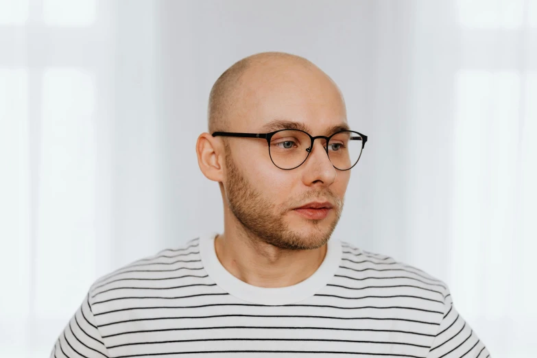 a bald man with a striped sweater has his hair shaved in half