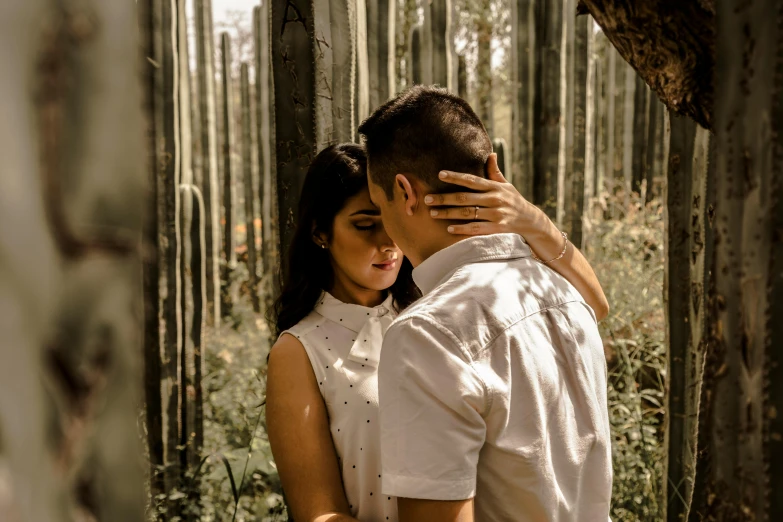 a man and woman stand in the middle of a forest while emcing