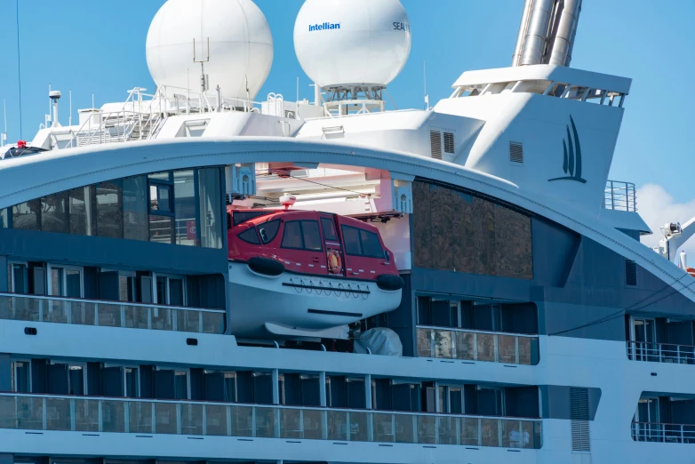 a cruise ship with red train going under the bridge