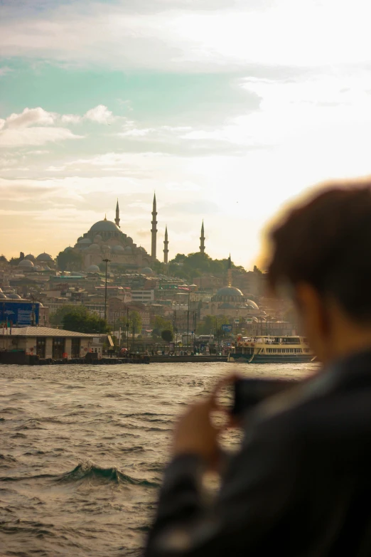 a person is looking out over the water with buildings and hills in the background