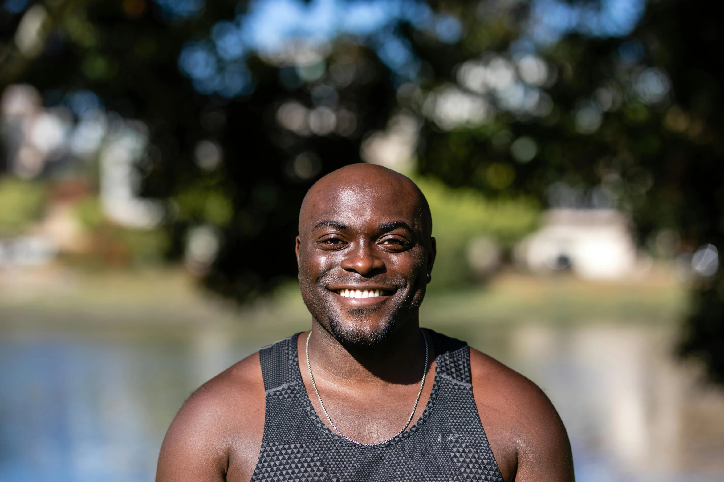 a smiling man in black shirt standing next to water