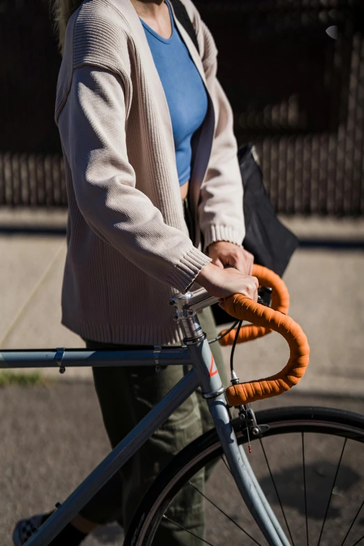 a woman is carrying an orange bike in the street