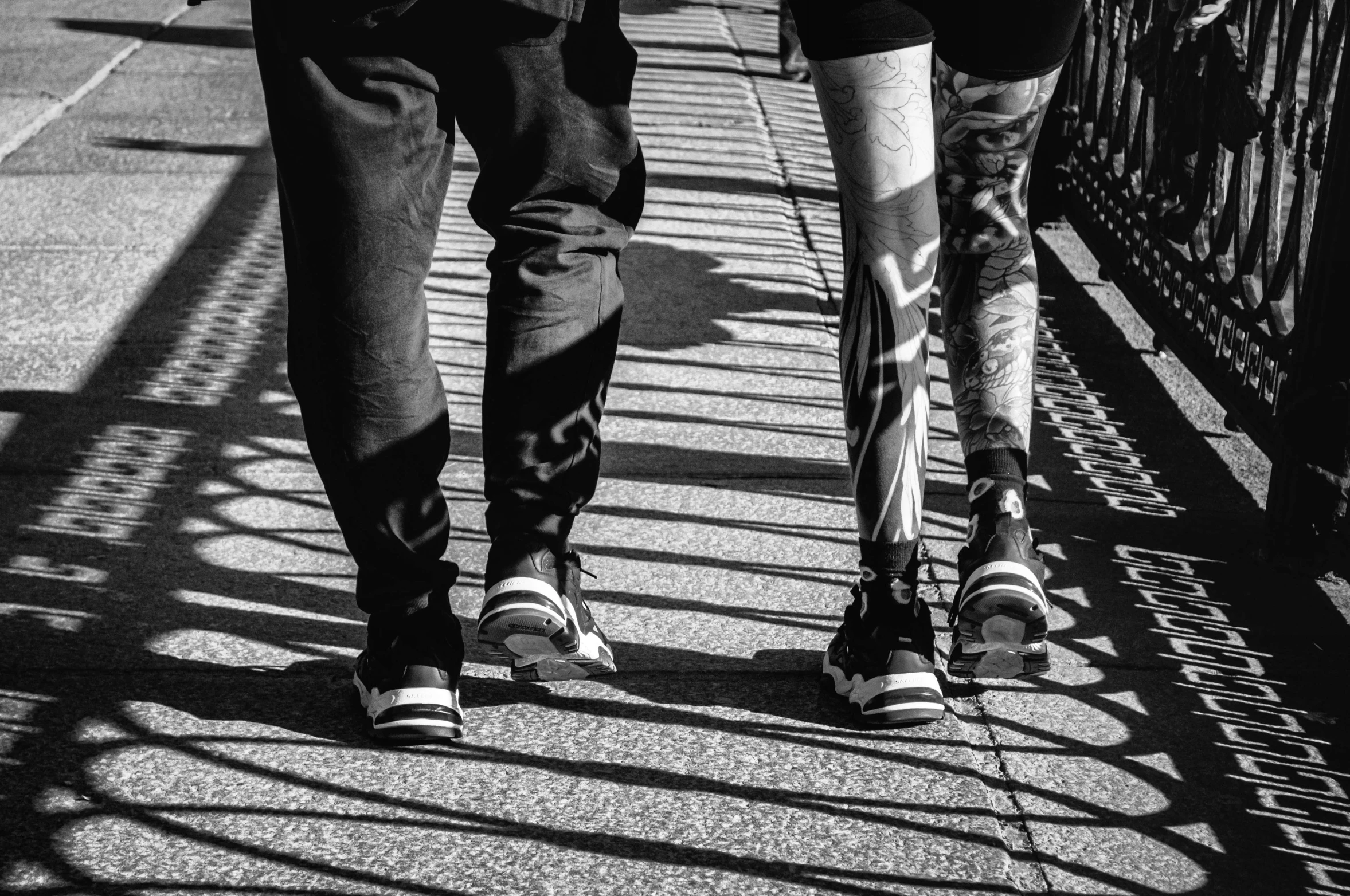 two people walking down a sidewalk with black and white pography