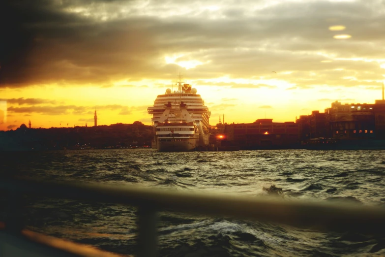 a large cruise ship traveling past a city at sunset