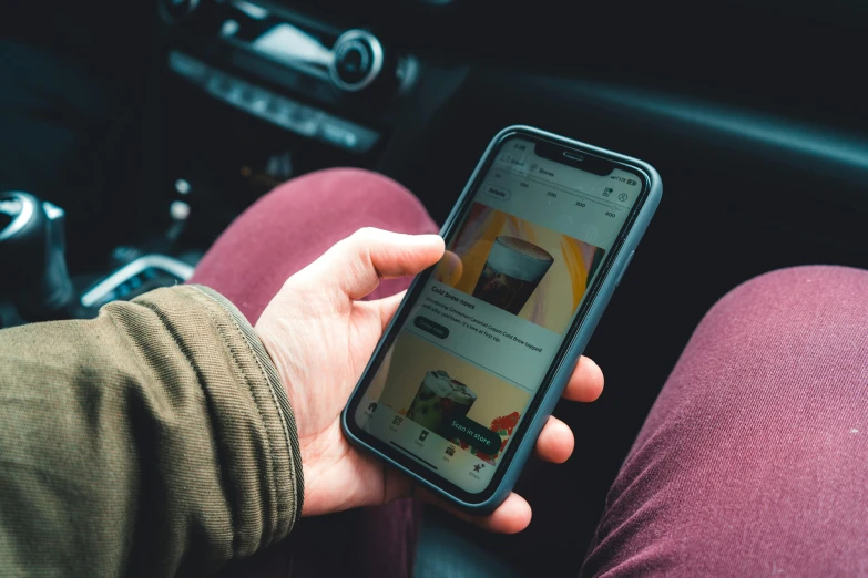 man with smartphone sitting in car holding up phone