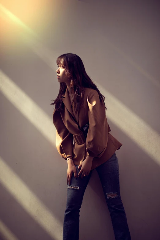 a woman standing by a wall wearing a leather jacket