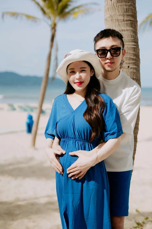 a beautiful young woman standing next to a young man in a hat and sunglasses