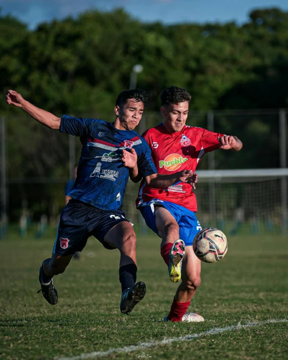 two boys playing soccer during the day at a sports field