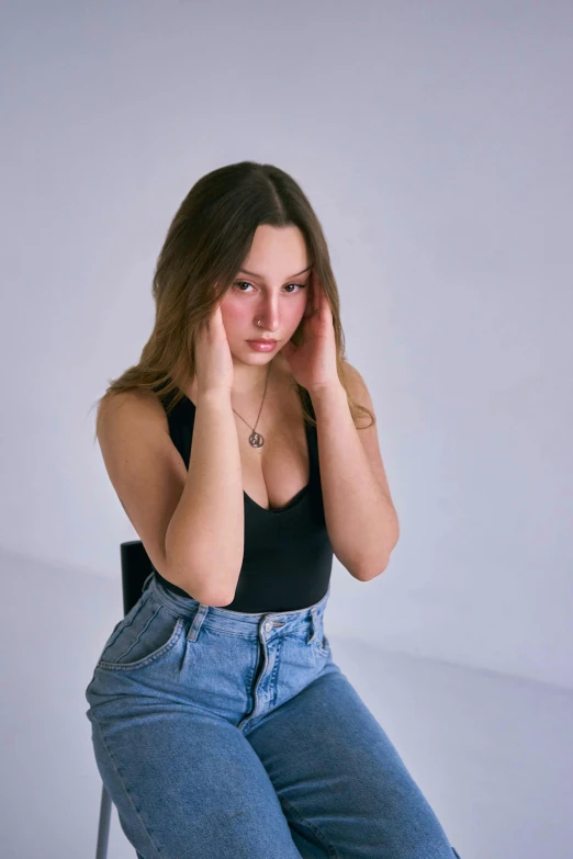 the woman is sitting on a stool and touching her head