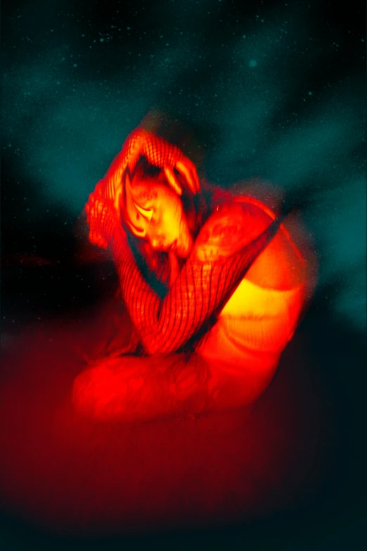 a woman holding her head and wearing a red sweater