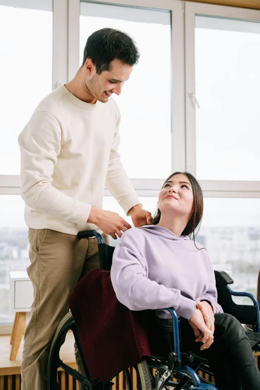 a woman in a wheelchair being assisted by a man