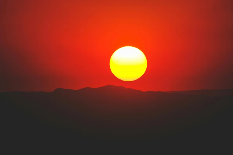 the sun shining through the clouds with mountains in the background