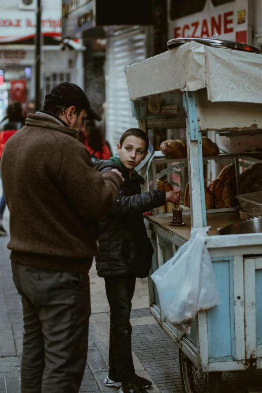 a man and a child stand in front of a street vendor