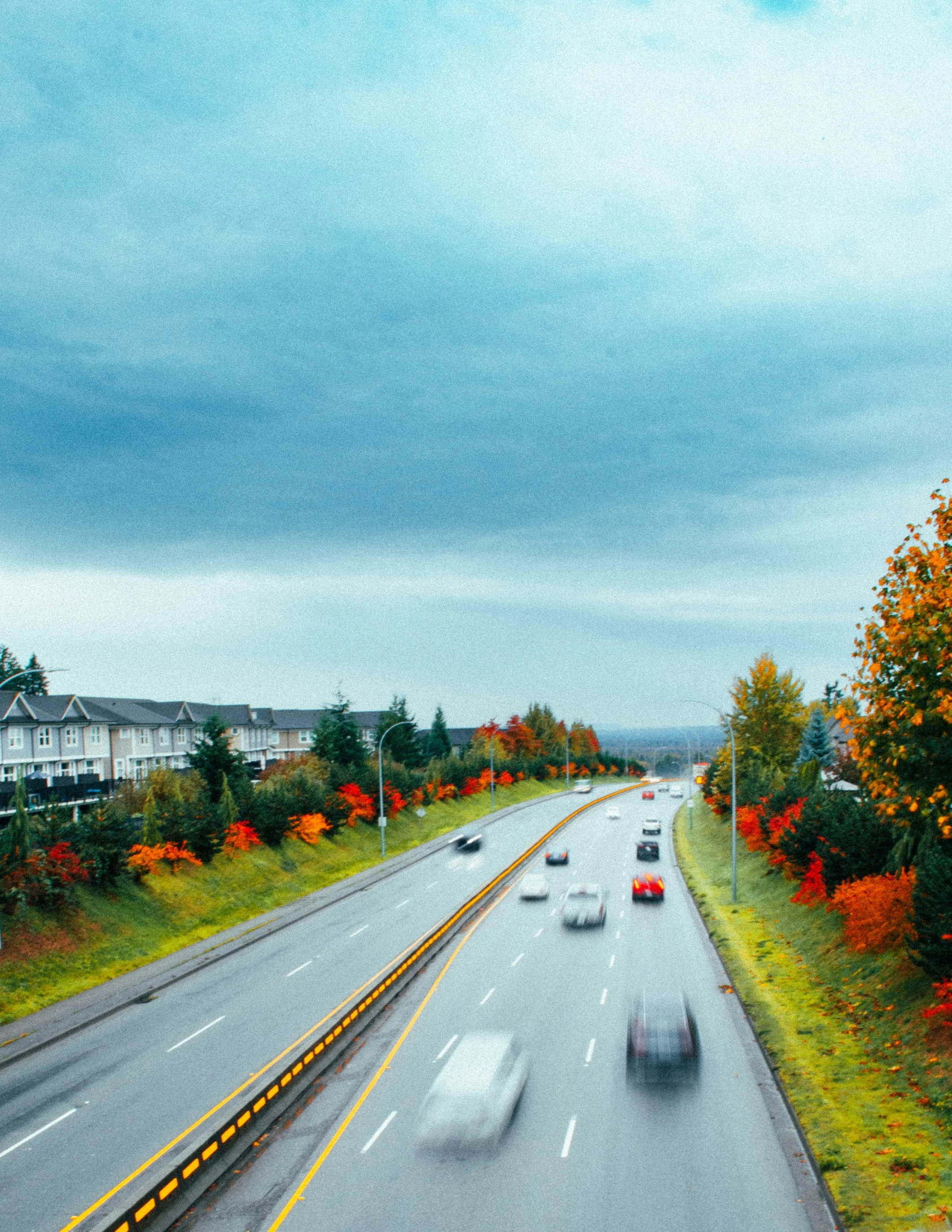 two cars traveling down an urban highway in the middle of autumn