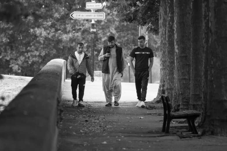 black and white pograph of people walking on sidewalk near street sign