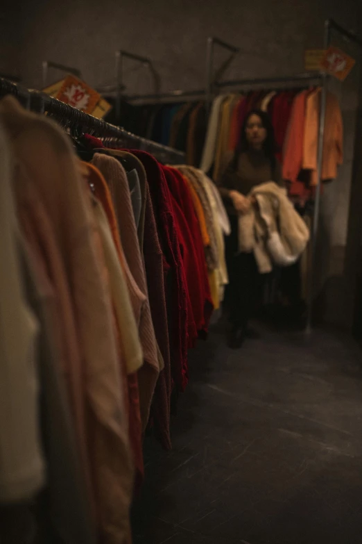a woman is looking through a rack of clothes