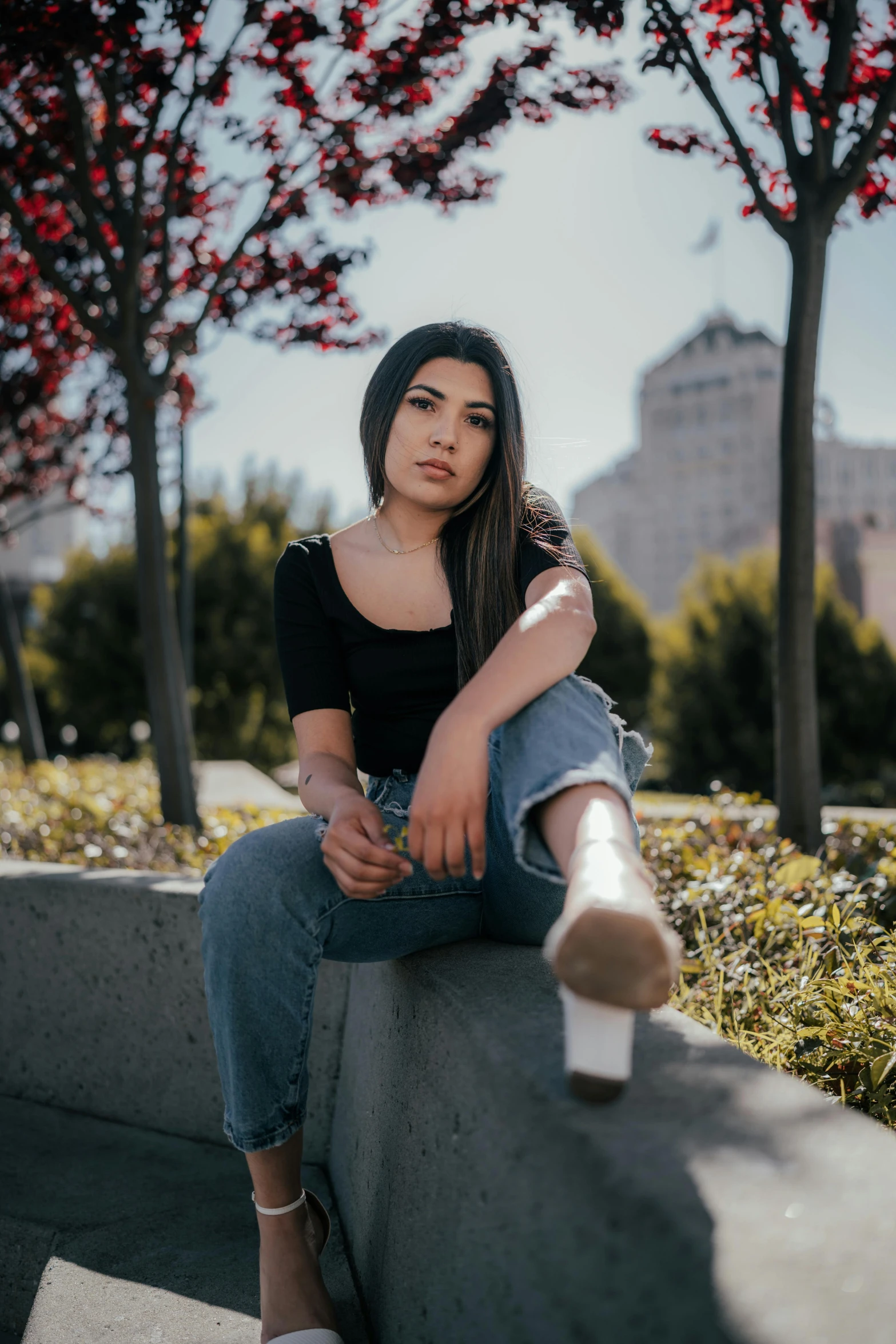 woman with long hair sitting on concrete in the park