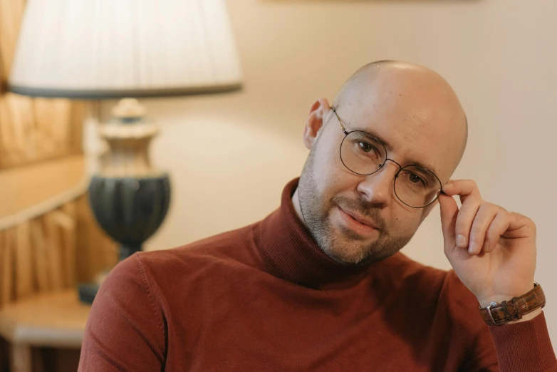 a balding man with glasses sitting in a room