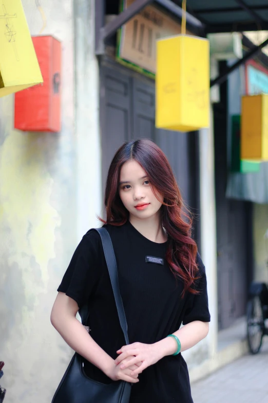 a woman standing on the sidewalk holding onto a black purse