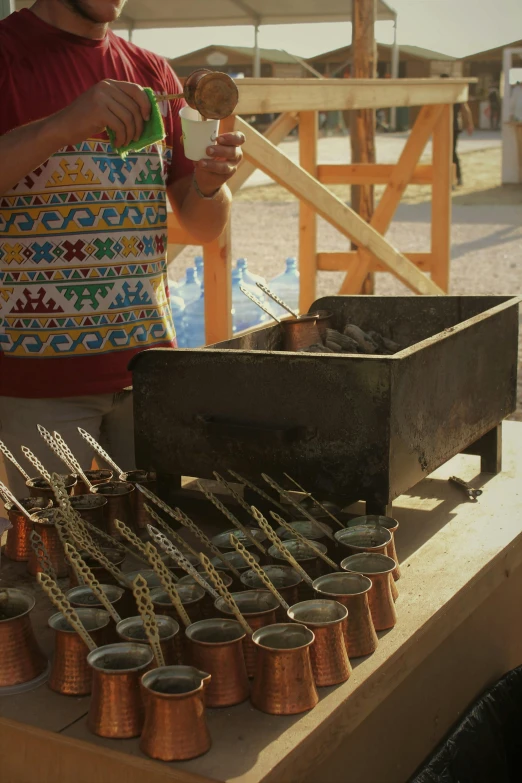 a man standing over a table filled with lots of pots and pans