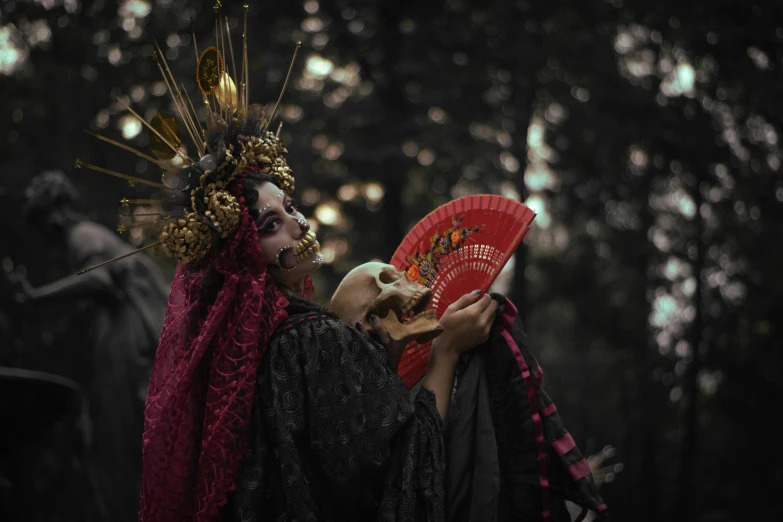 a woman in costume holds up her red oriental fan