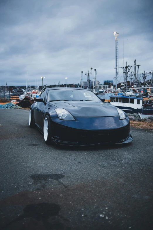 a very nice car with chrome rims parked by some docks