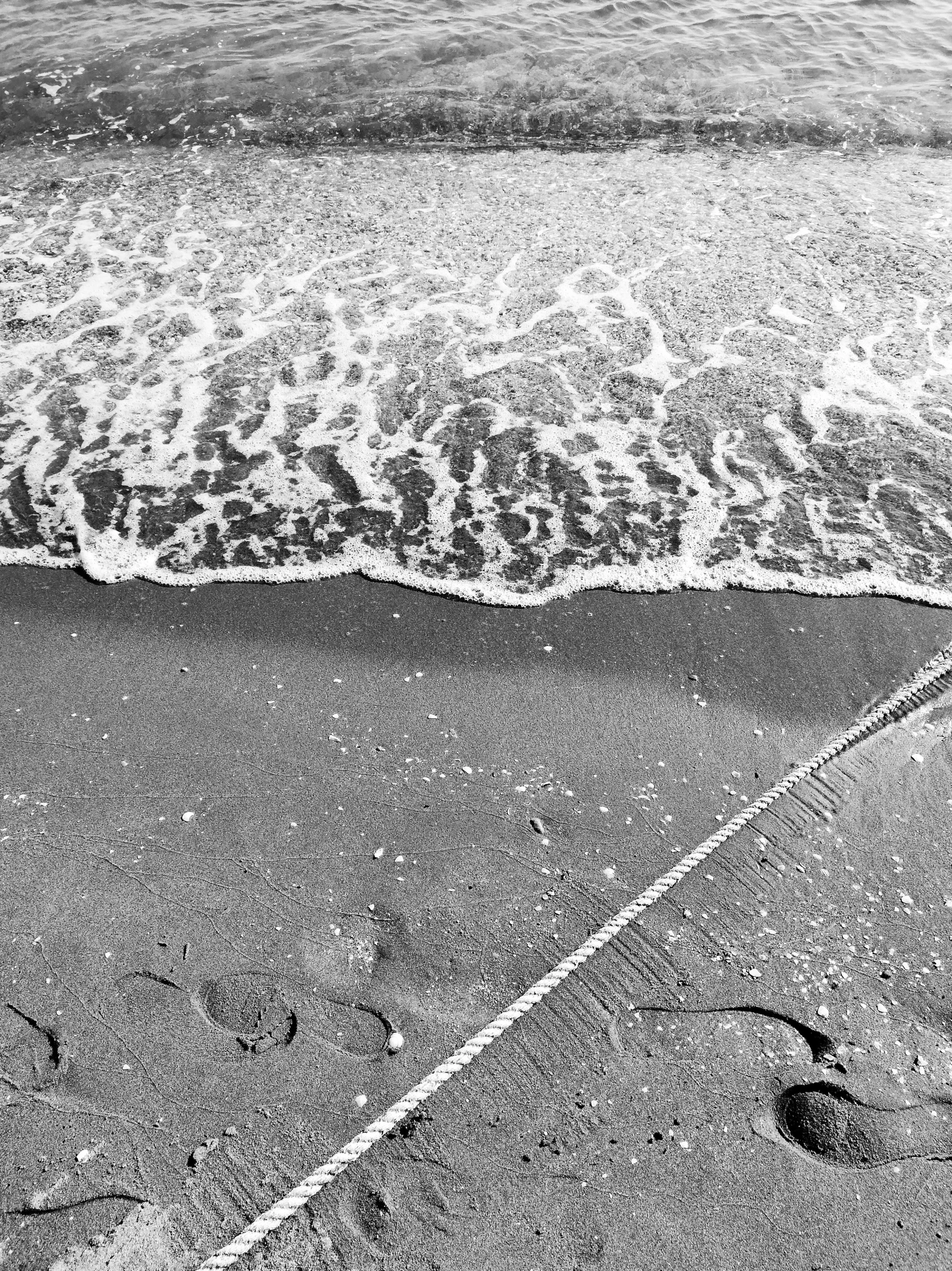 the feet of a person are next to the waves on a beach