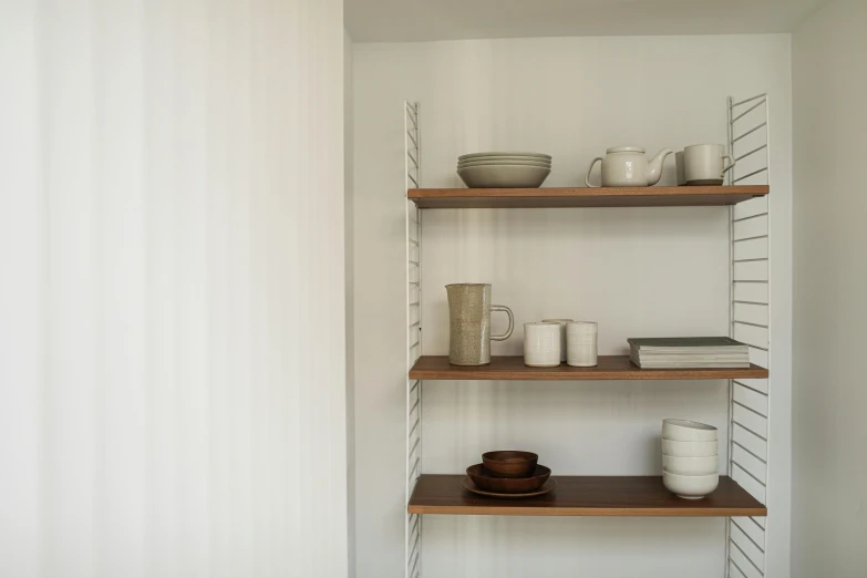 the shelf shelves in the bathroom have cups and a bowl on top of them