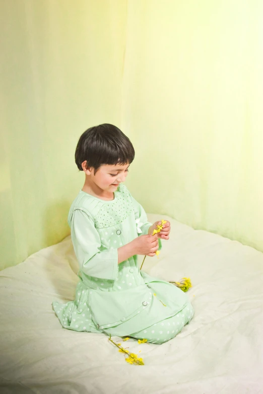 small boy sitting on the ground with a flower in his hand