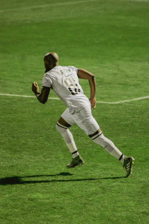 a man running across a soccer field wearing white