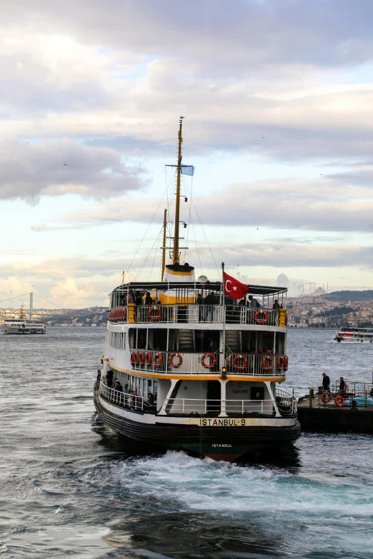 a ship with people on deck sitting in the water