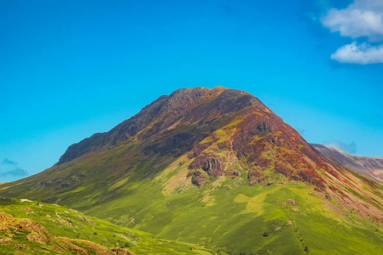 a mountain top is in the middle of a grassy field