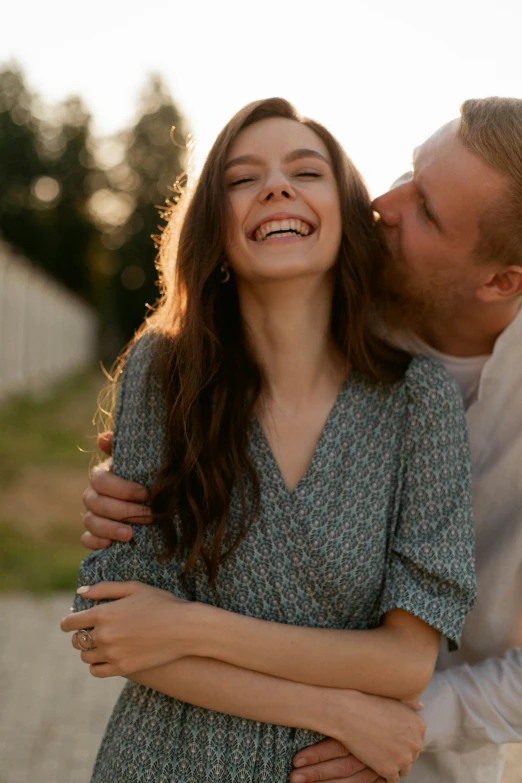 a man and a women standing by each other as one kisses the cheek