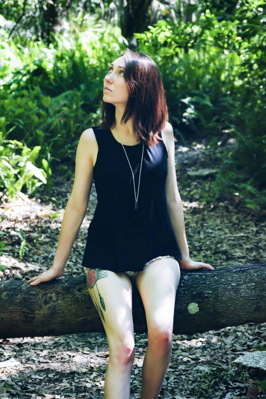 woman sitting on a log in a forest looking away