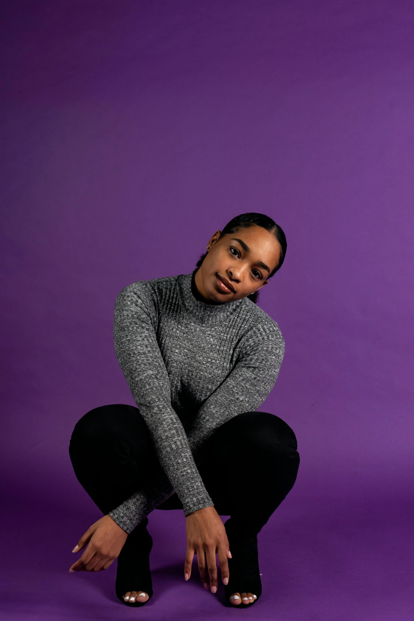 a man posing in a studio in front of a purple backdrop