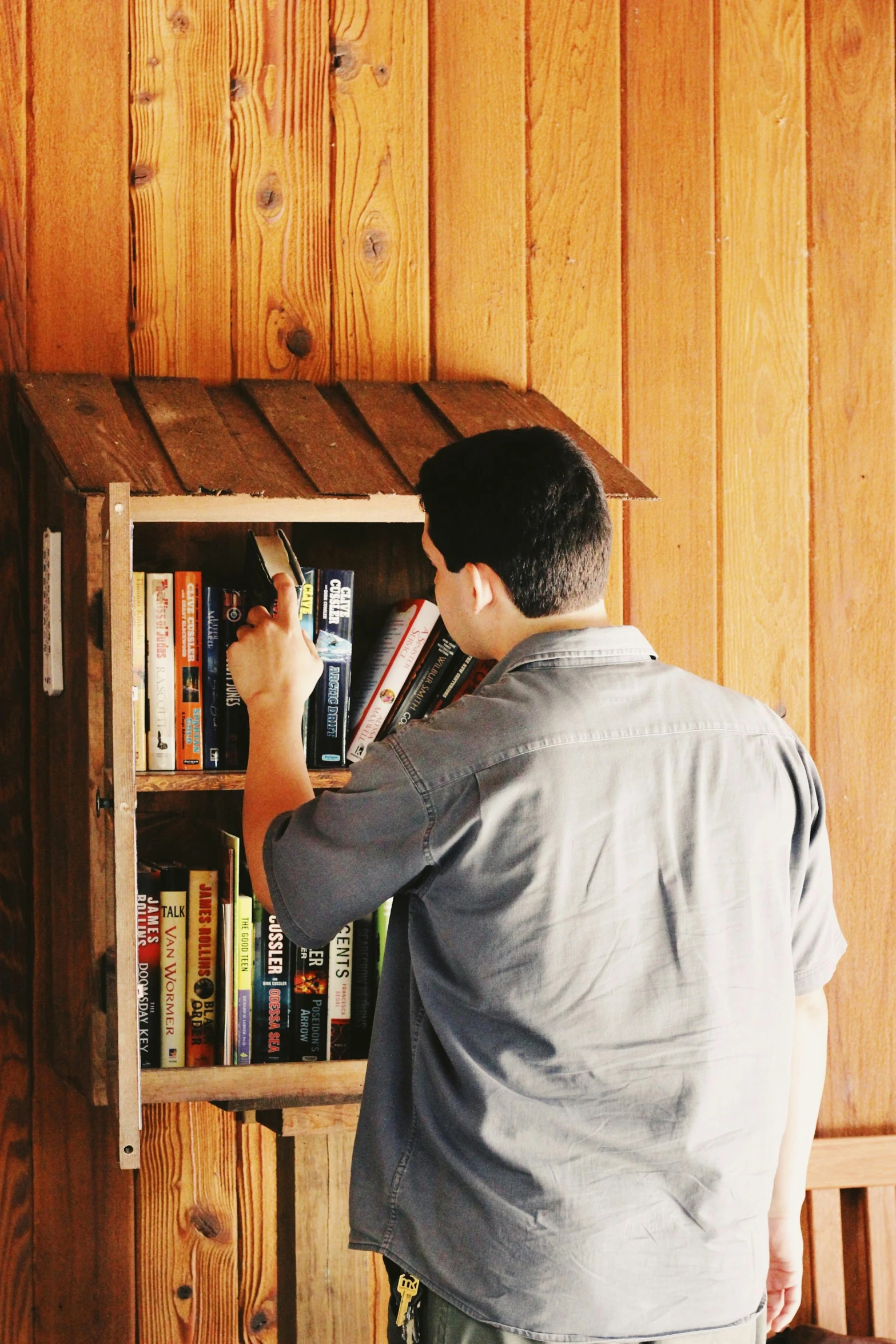 the man is holding onto a book shelf that has a lot of books