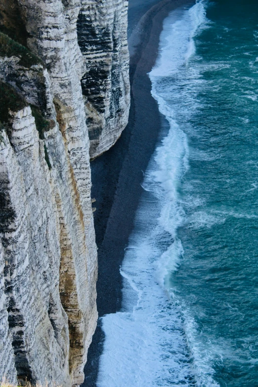 the ocean on the side of a cliff with a couple people climbing