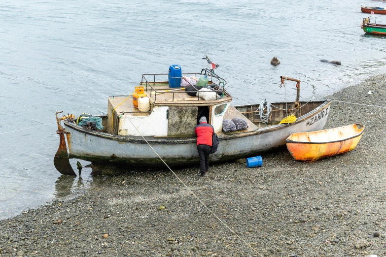 a boat sitting on top of a beach next to a body of water