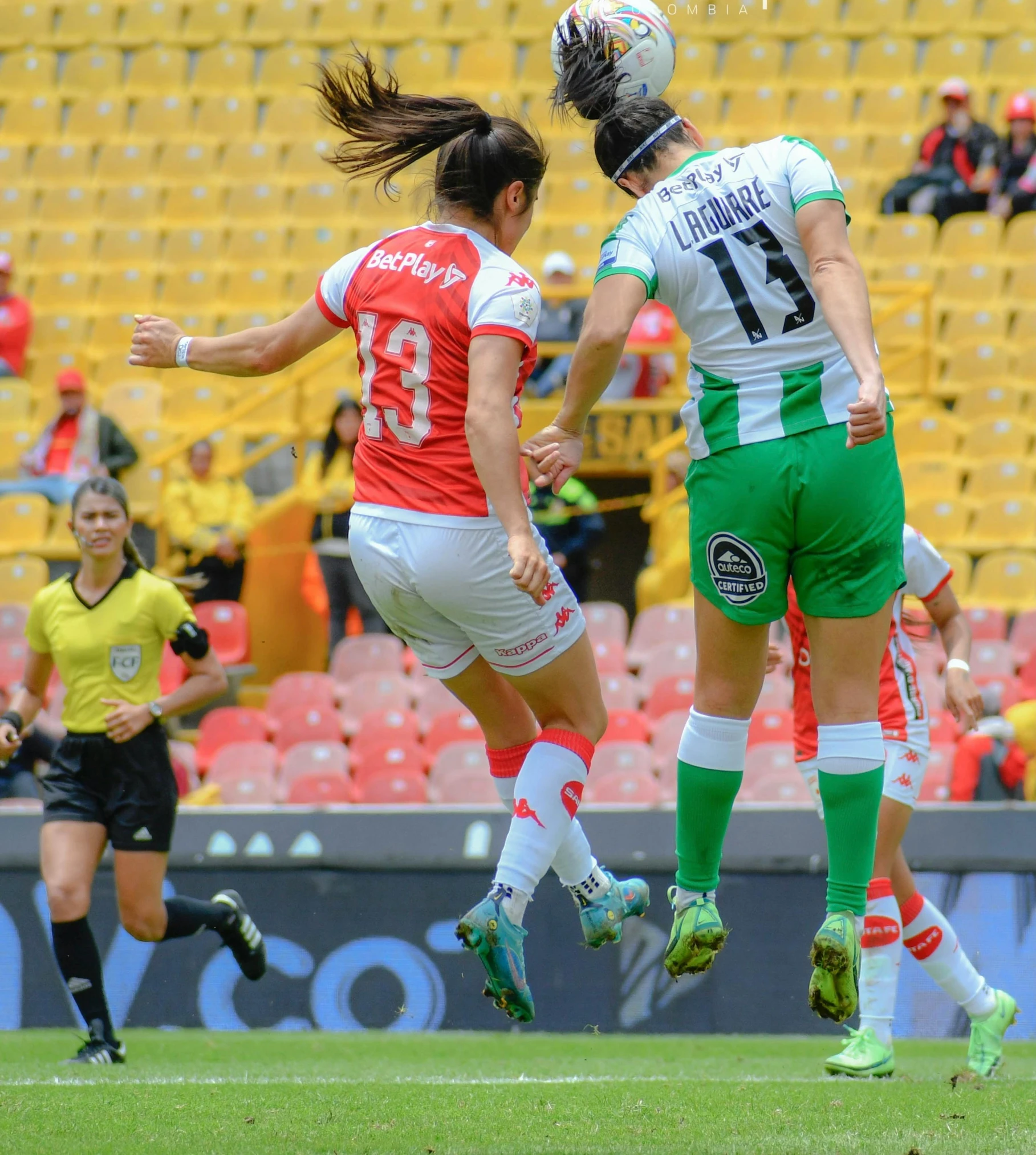 two female soccer players jump up and head the ball