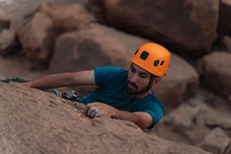 a man climbing on a rock with a helmet on