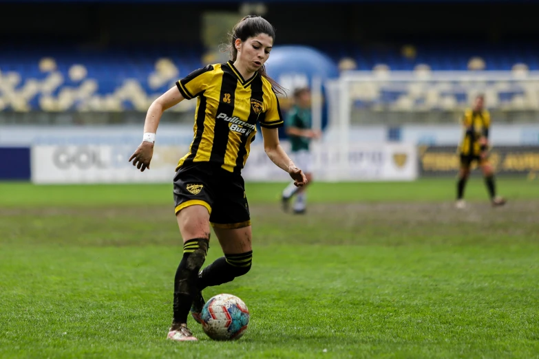 a woman in yellow and black uniform playing soccer