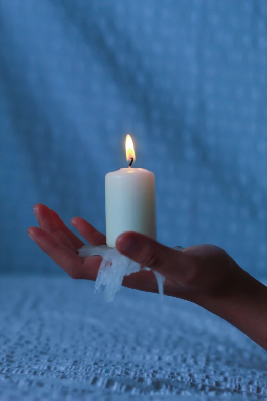 a person holds a candle in their left hand