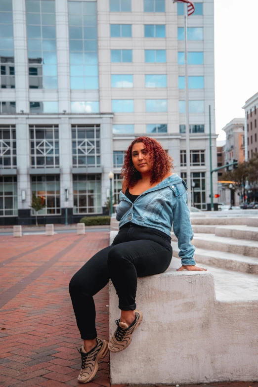 a woman sitting on a cement pillar in front of a building