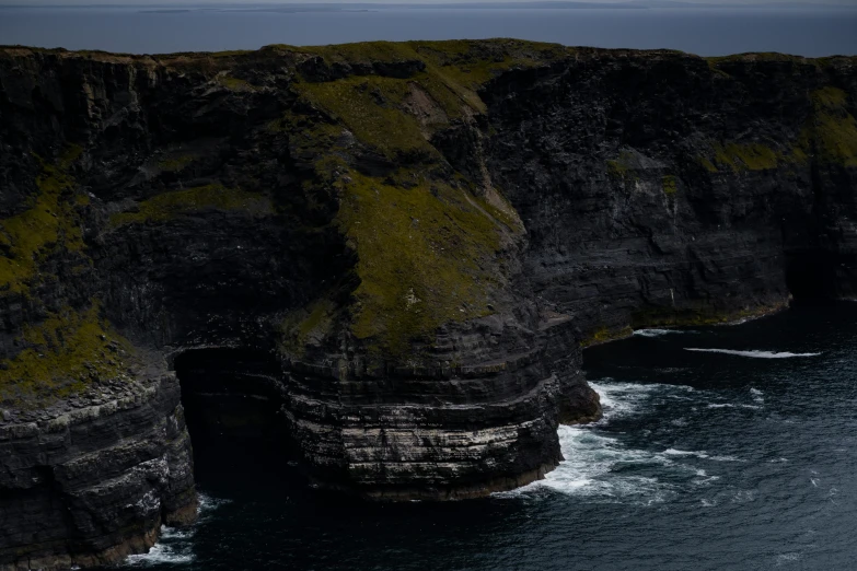 two cliffs, each one high up and the other out with green vegetation growing all over them