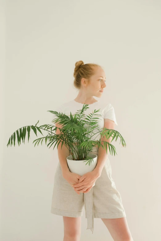 the young woman is holding up a green plant