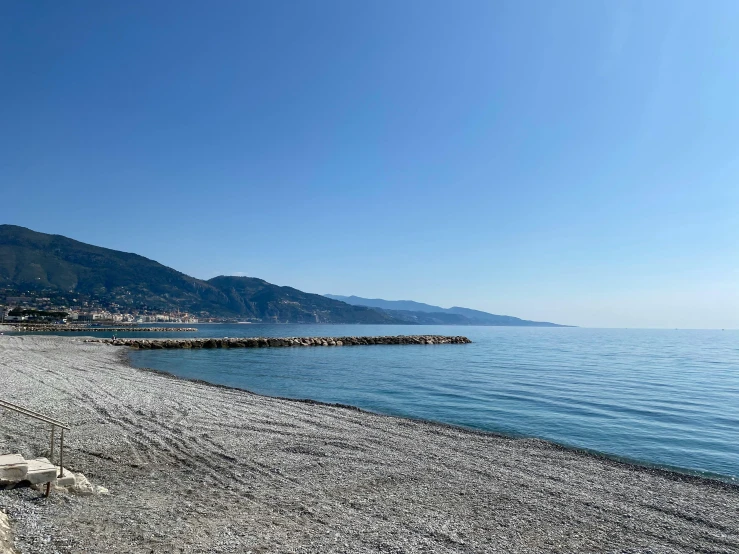 a white beach with water and rocks on the beach