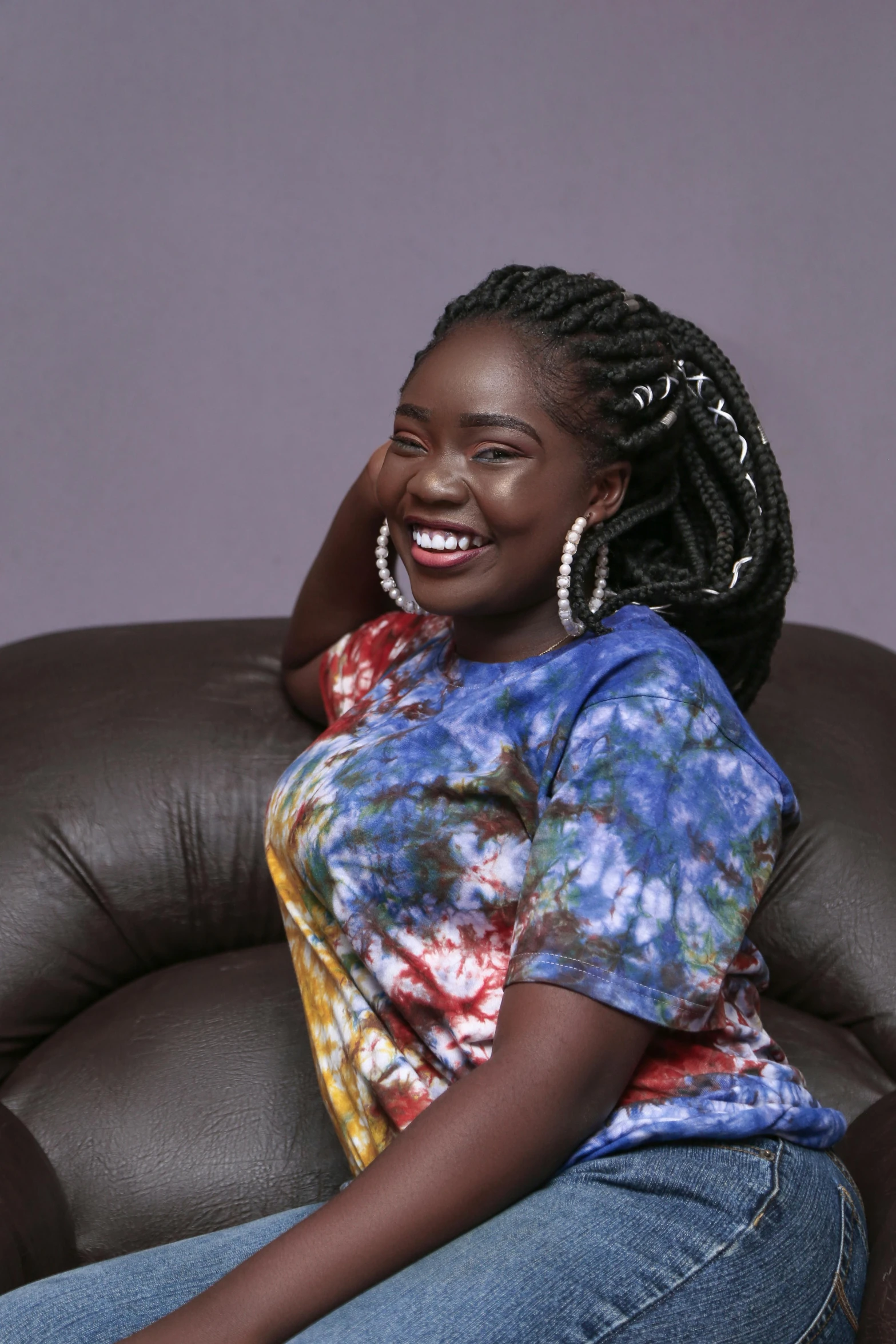 a woman is sitting on a brown leather chair with her hair in an afro curl