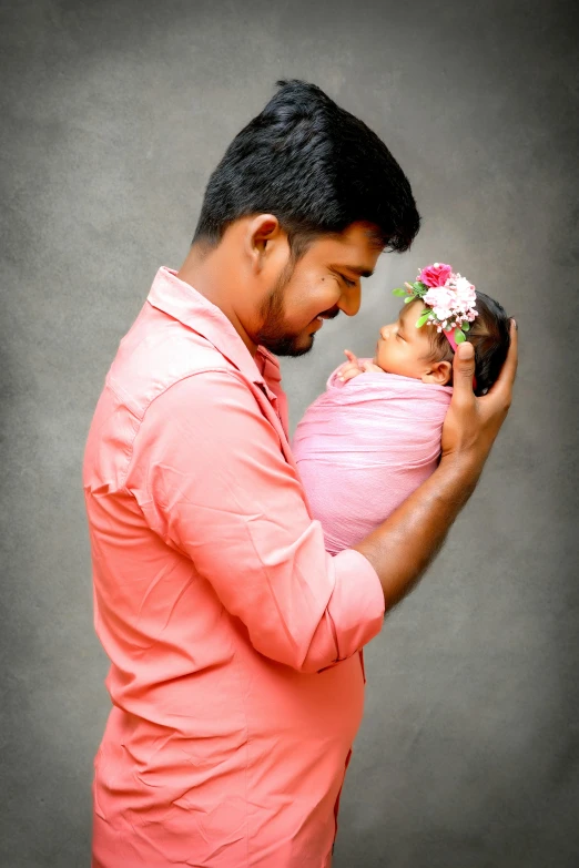 a man in pink shirt holding a baby