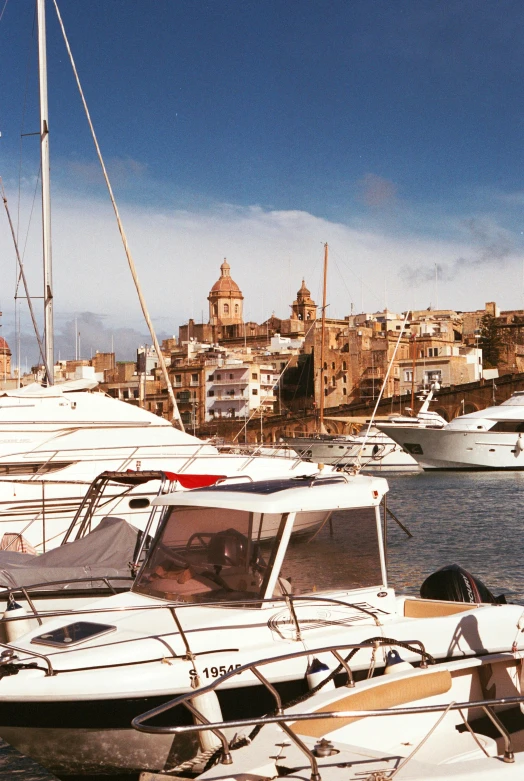 several white yachts parked in a harbor with a town in the background